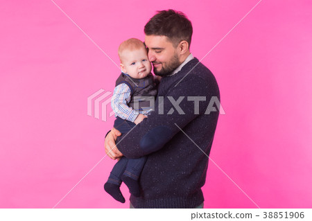Happy father holding baby son in hands over pink Happy father holding baby son in hands over pink 38851906