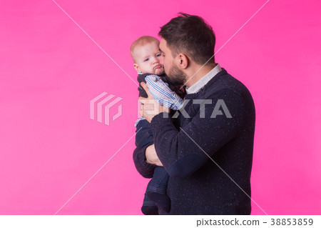 Happy father holding baby son in hands over pink Happy father holding baby son in hands over pink 38853859