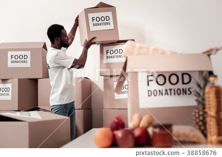 Serious volunteer collecting parcels with food Serious volunteer collecting parcels with food 38858676