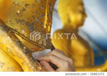 Gilding gold leaf to Buddha for worship.  38861372
