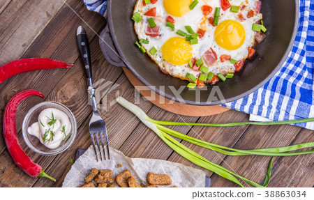 Fried eggs in pan with tomatoes and green fresh 38863034