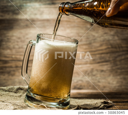 Beer from bottle filled into mug standing on Beer from bottle filled into mug standing on 38863045