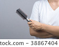 Woman hand holding black round comb or hairbrush 38867404