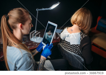 Tattooist makes shoot of tattoo on client back 38867919