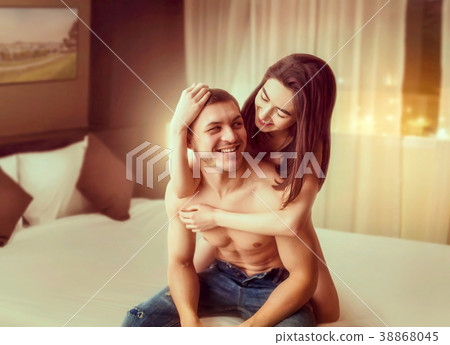Happy love couple hugging on big white bed 38868045