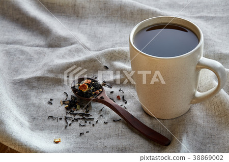 Ceramic cup of tea with scattered tea leaves on a 38869002
