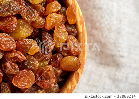 Wooden bowl with golden raisins on light 38869214