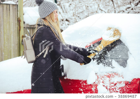 Winter portrait of a young woman cleaning snow Winter portrait of a young woman cleaning snow 38869487