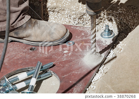 The builder uses a drill to make holes in a The builder uses a drill to make holes in a 38870268