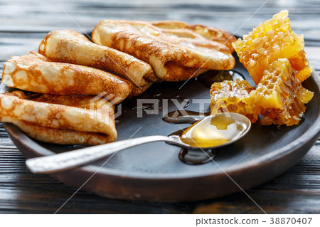 Crepes with honey on a wooden plate. 38870407