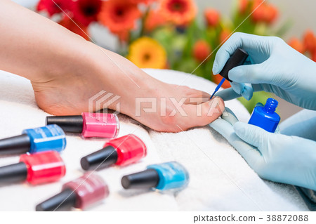 Hands of a nail technician polishing the toenails 38872088