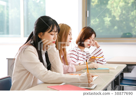 Campus life - female students in a classroom during class, studying together and taking selfie through mobile phone. 262 Campus life - female students in a classroom during class, studying together and taking selfie through mobile phone. 262 38877690