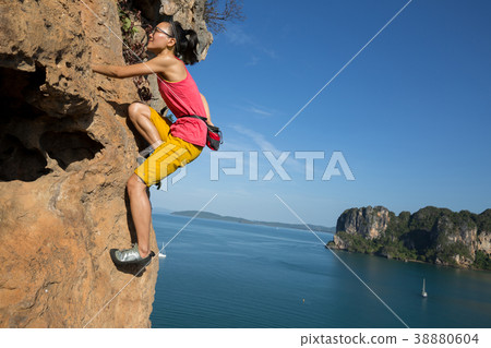 female rock climber climbing on seaside cliff female rock climber climbing on seaside cliff 38880604