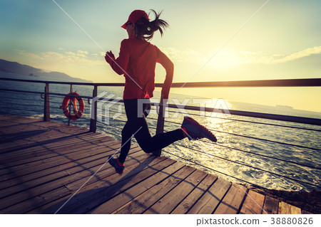 running on seaside boardwalk during sunrise 38880826