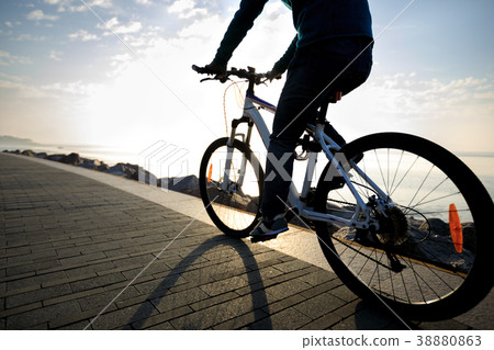 cyclist riding bike in the sunrise coast path cyclist riding bike in the sunrise coast path 38880863