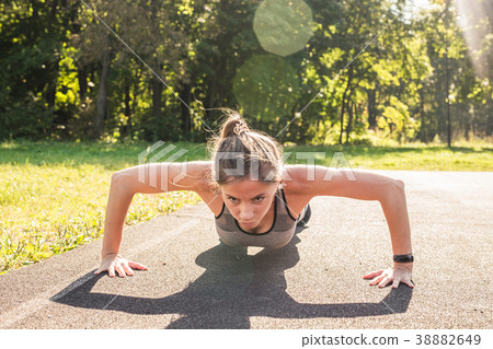 Fit woman doing push-ups at the park. 38882649