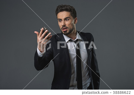 Surprised man looking at alarm clock Surprised man looking at alarm clock 38886622