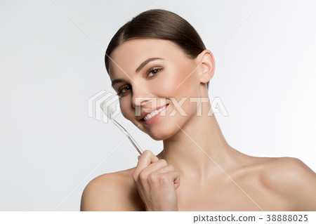 Joyful young woman holding toothbrush 38888025