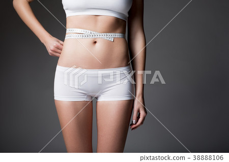 Slender young woman measuring figure by tape 38888106