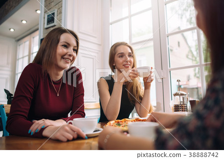 Female friends drinking coffee having a pleasant Female friends drinking coffee having a pleasant 38888742