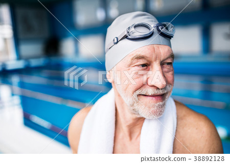 Senior man standing in an indoor swimming pool. Senior man standing in an indoor swimming pool. 38892128
