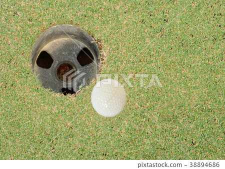 golf ball rolling near hole in course field 38894686