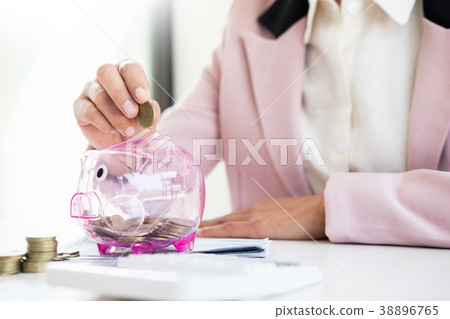 Close up of Businessman putting coin into small piggy bank , The 38896765