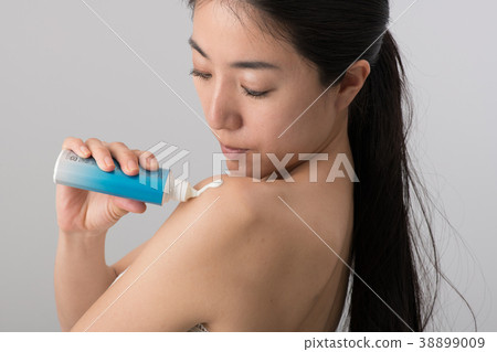 Young woman applying sunscreen on her arm 38899009