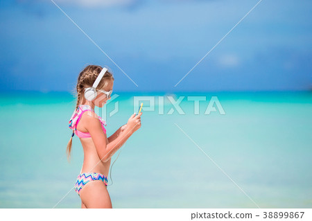 Little girl with headphones on the beach Little girl with headphones on the beach 38899867