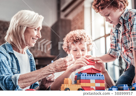 Joyful aged woman playing with her grandchildren Joyful aged woman playing with her grandchildren 38899957