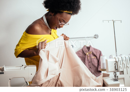 african woman seamstress looking at pink fabrics 38903125