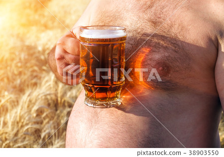 large glass of light beer is held by a fat man large glass of light beer is held by a fat man 38903550