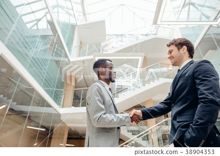 two multiracial businessmen handshaking in modern 38904353