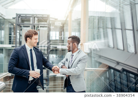 two multiracial businessmen handshaking in modern 38904354