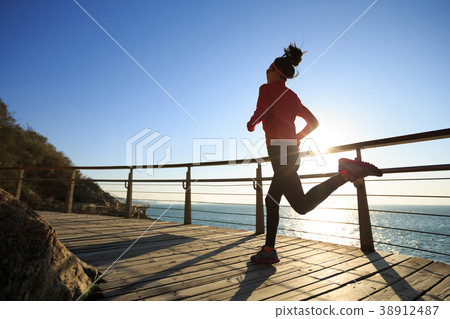 jogger run on seaside boardwalk during sunrise 38912487