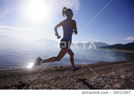 woman running on rocky seaside woman running on rocky seaside 38912807