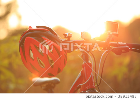 red helmet hang on mountain bike in the sunrise  38913485
