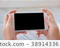 Man hand holding white smart phone with blank screen on backgrou 38914336
