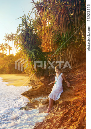 A woman sits at the foot of a cliff A woman sits at the foot of a cliff 38923326
