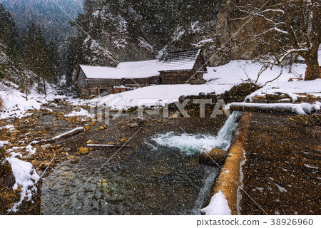 Old wooden water mill in winter with snow falling 38926960