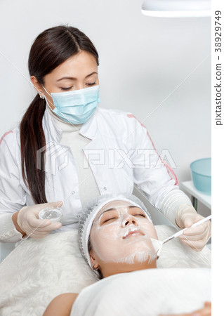 cosmetologist puts a mask on the face cosmetologist puts a mask on the face 38929749