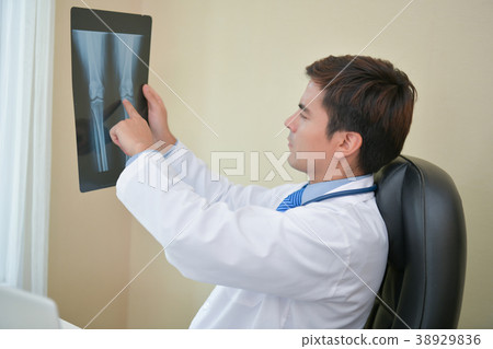 Smiling doctor posing in the office, he is wearing a stethoscope Smiling doctor posing in the office, he is wearing a stethoscope 38929836