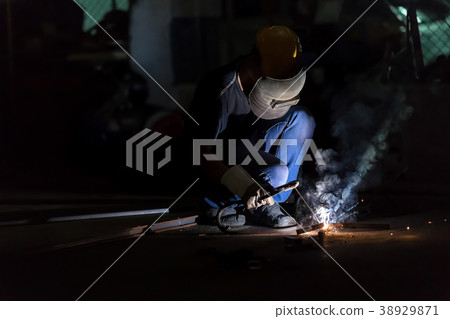 Craftsman in a welding mask and welders leathers. 38929871