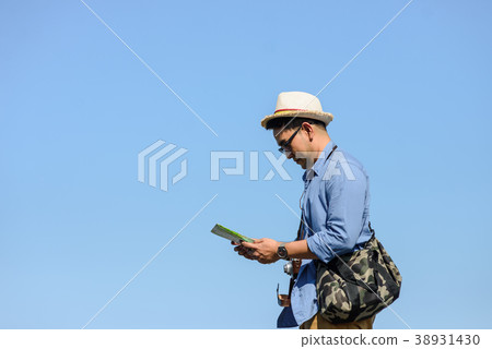 Asian tourist holding map with blue sky in sunny Asian tourist holding map with blue sky in sunny 38931430