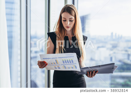 Female financial analyst holding papers studying 38932814