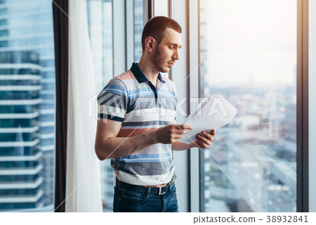 Businessman holding reading documents standing by 38932841