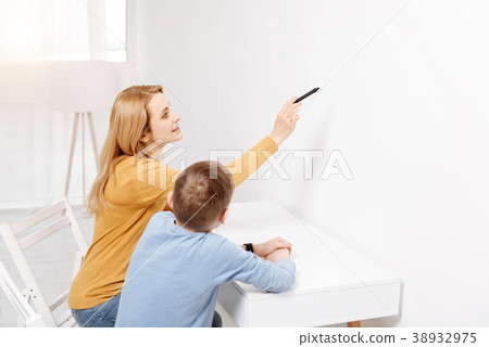 Joyful smart woman pointing at the wall 38932975