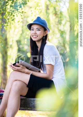 Asian woman using a tablet PC outdoors Asian woman using a tablet PC outdoors 38933990