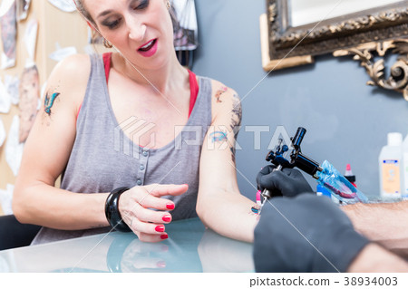 Close-up of the hand of a tattoo artist shading a Close-up of the hand of a tattoo artist shading a 38934003