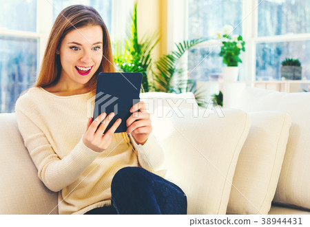 Young woman reading with an e-reader in a large Young woman reading with an e-reader in a large 38944431